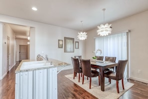 A modern kitchen with a granite countertop, stainless steel sink, and a dining area with a wooden table and chairs.