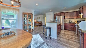 Una cocina amplia con armarios de madera, una isla central y una zona de comedor con mesa y sillas de madera.