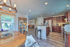 A spacious kitchen with wooden cabinets, a central island, and a dining area with a wooden table and chairs. - Peaceful Portales Escape w/ Patio & Grill! (Portales)