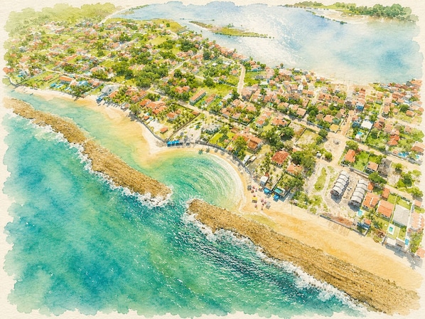 An aerial view of a coastal town with beachfront properties, a sandy beach, and a rocky shoreline.