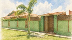 A house with a tiled roof, a green wall, and a palm tree in the front yard.