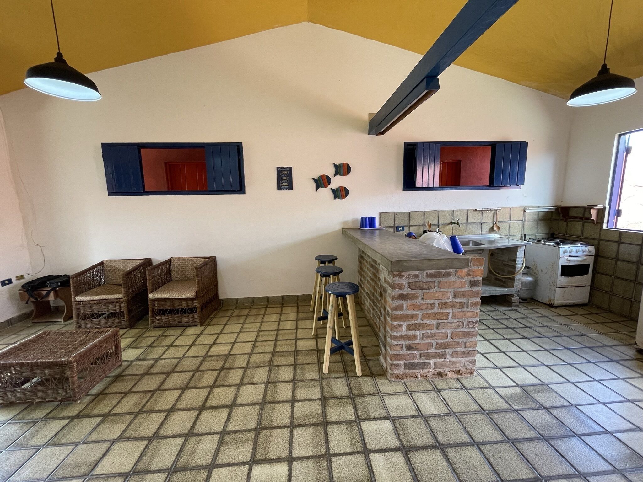 A kitchen with a brick island, two hanging pendant lights, a gas stove, and a tiled floor.