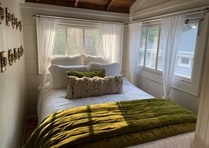 Een slaapkamer met een groot bed, witte gordijnen en uitzicht.