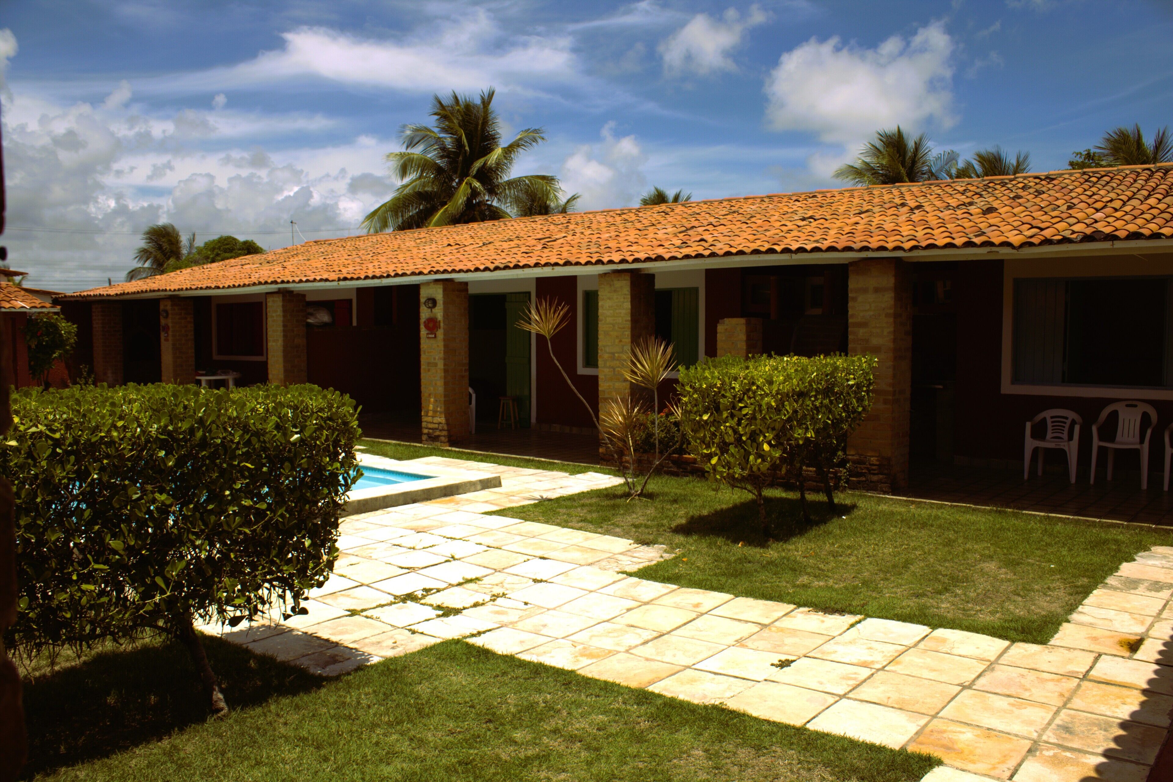 A building with a tiled roof, a swimming pool, and a well-maintained lawn.