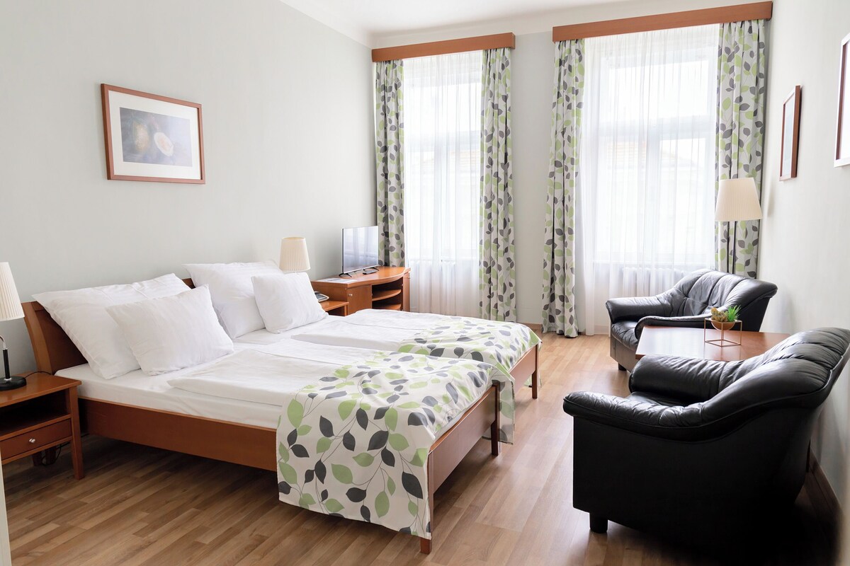 Una habitación de hotel con cama, escritorio, silla y sofá.