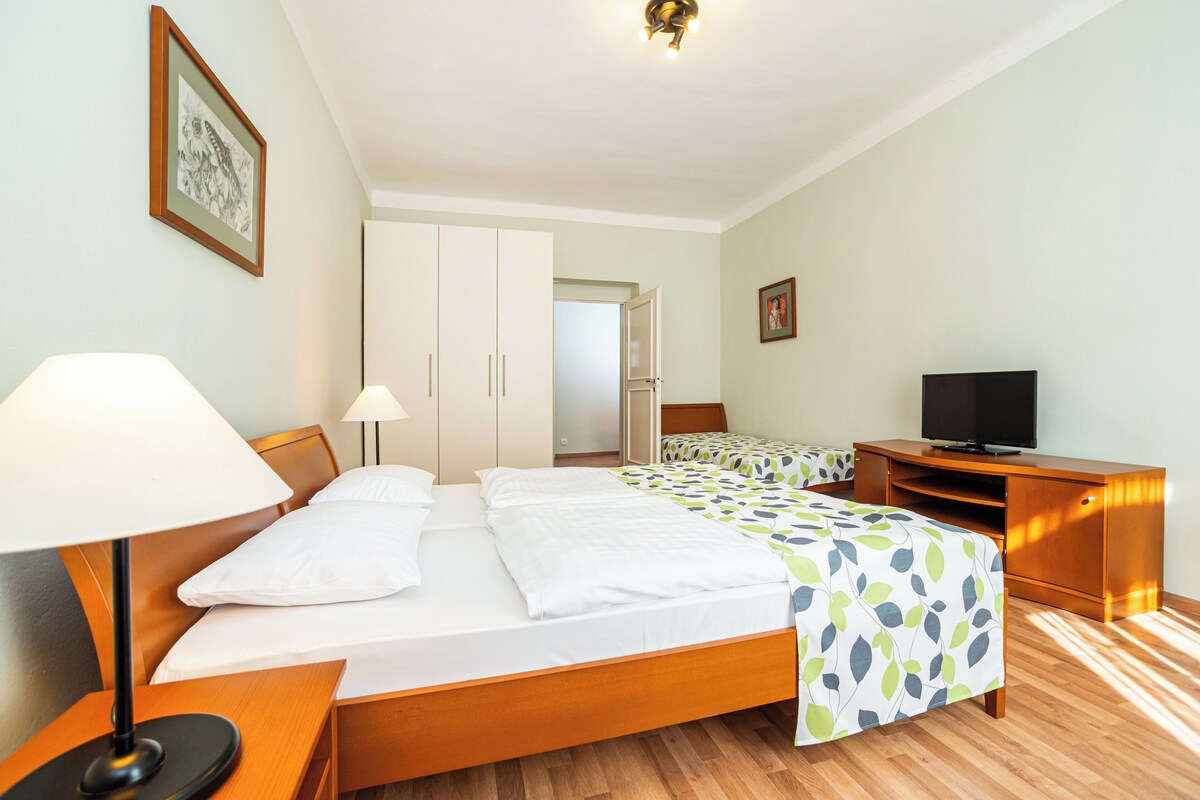 Una habitación de hotel con cama, lámparas de noche, televisor y armario.