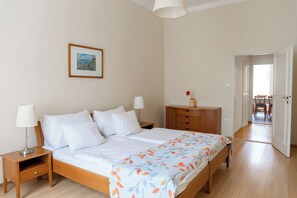A bedroom with a bed, nightstands, a dresser, and a door leading to another room. - Orion (Prague)