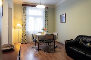A dining area with a table, chairs, a lamp, and a sofa. - Orion (Prague)