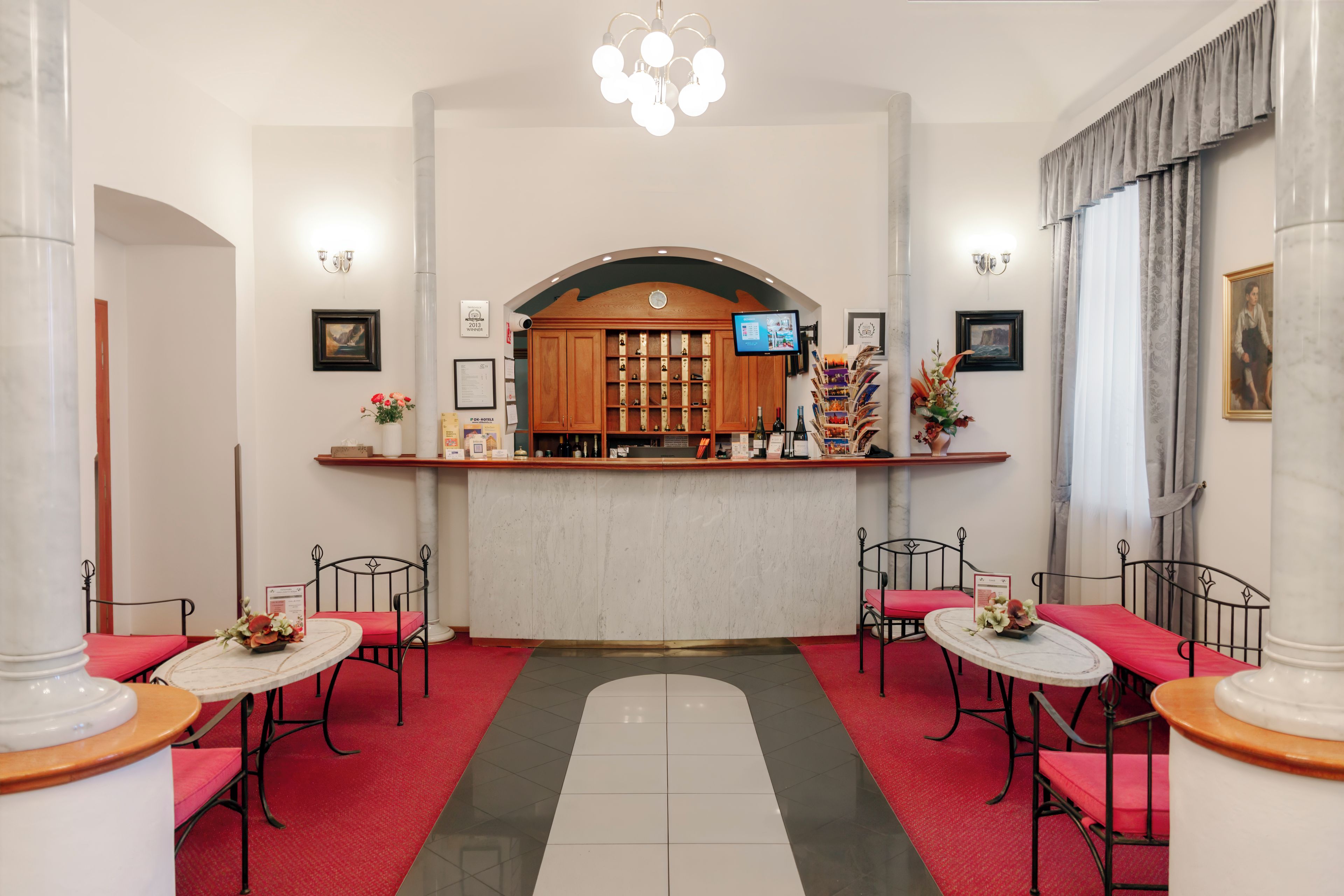 Eine Hotelhalle mit Empfangstresen, einer Sitzecke und einer großen Chandelüster.