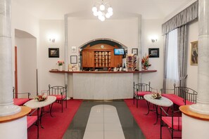Un vestíbulo de hotel con recepción, zona de estar y una lámpara de araña grande.