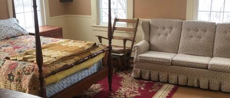 A bedroom with a four-poster bed, a sofa, a chair, and a table.