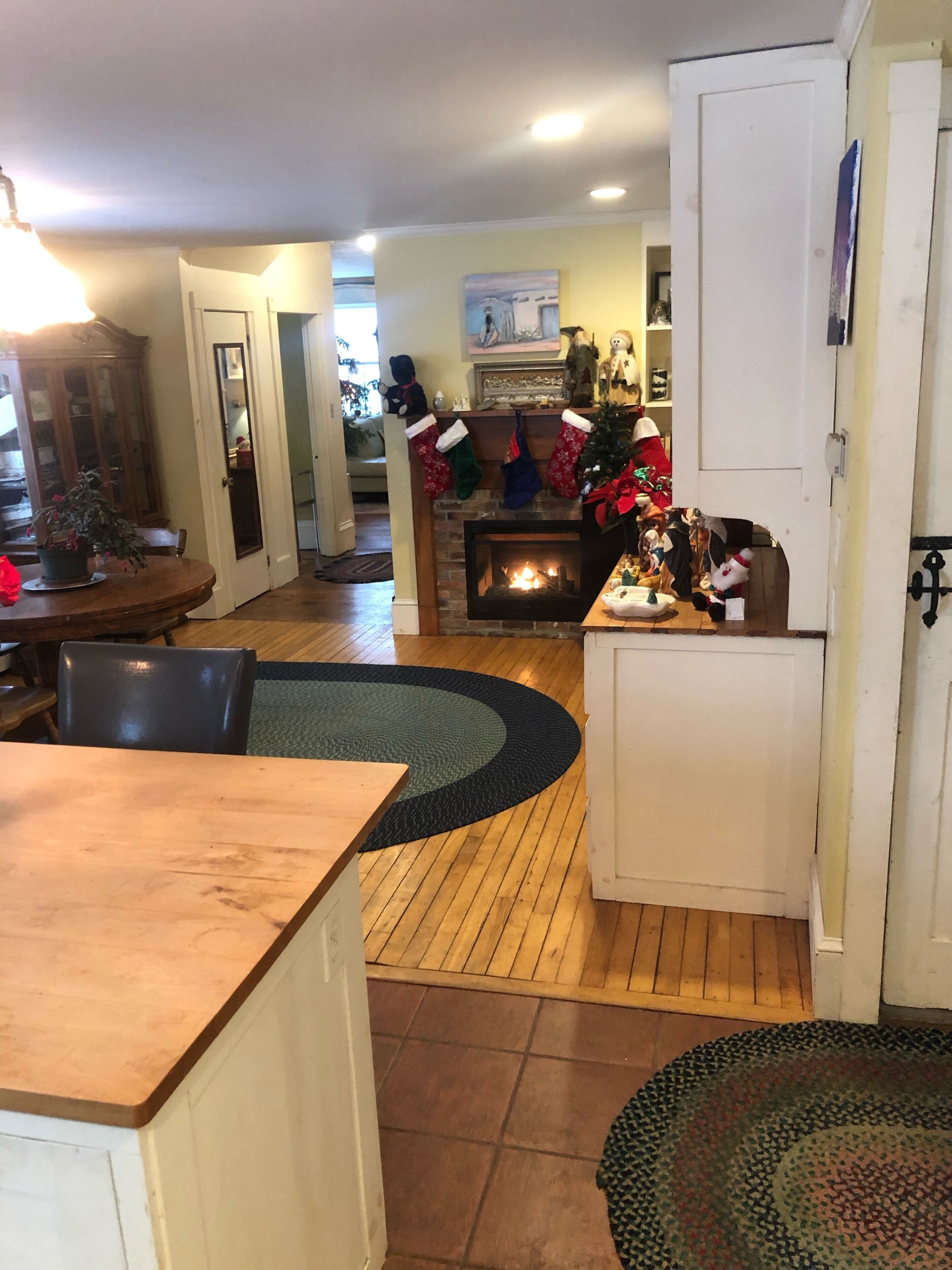 Un salon chaleureux avec une cheminée, un plancher en bois et un coin repas comprenant une table et des chaises.
