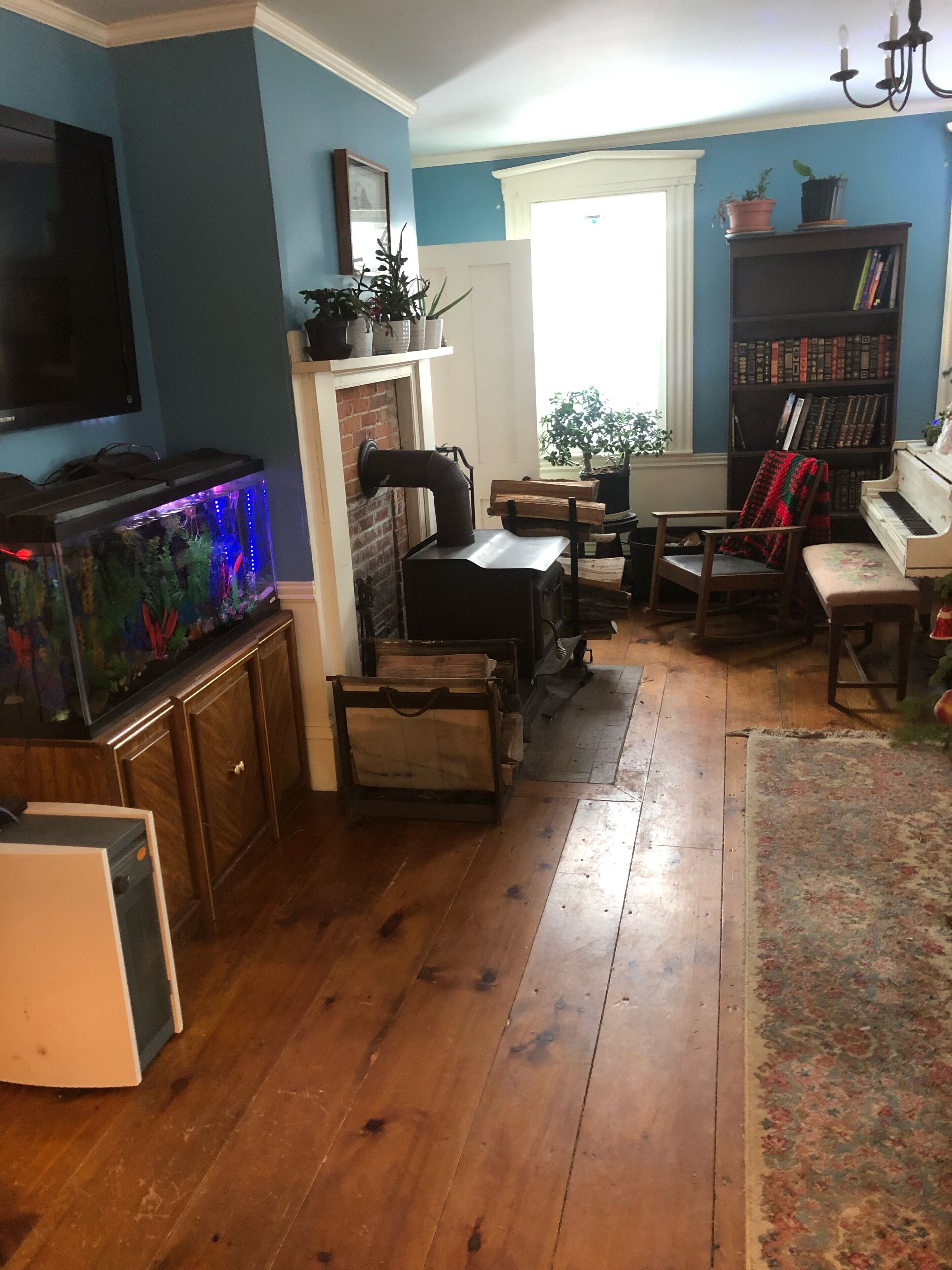 A living room with a fireplace, wooden furniture, a bookshelf, and an aquarium.
