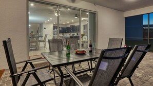 Een terras met een tafel voor vier personen, inclusief een fles champagne en glazen, en een uitzicht op het huis via een glazen deur.
