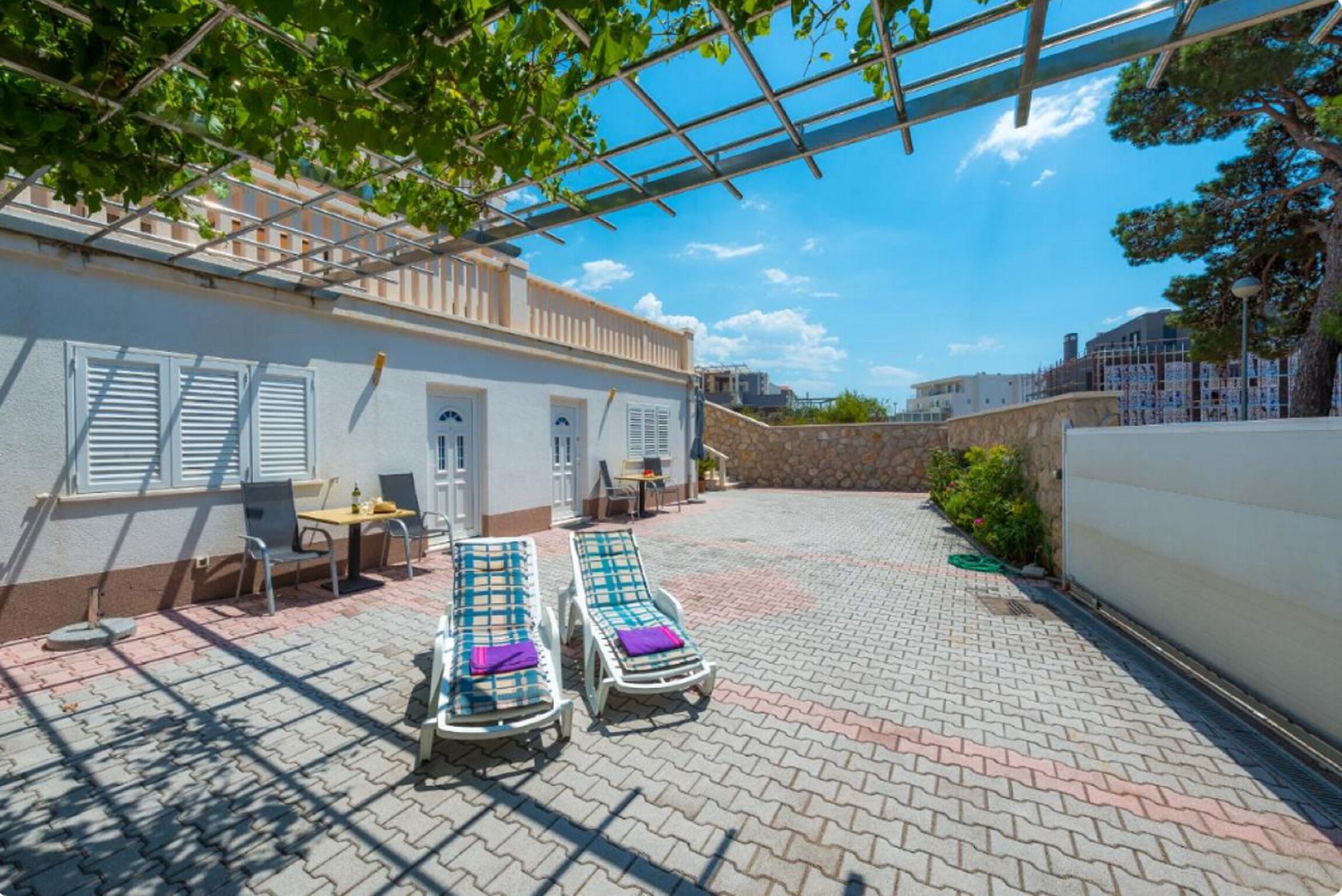 A courtyard with two sun loungers, a table, and chairs.