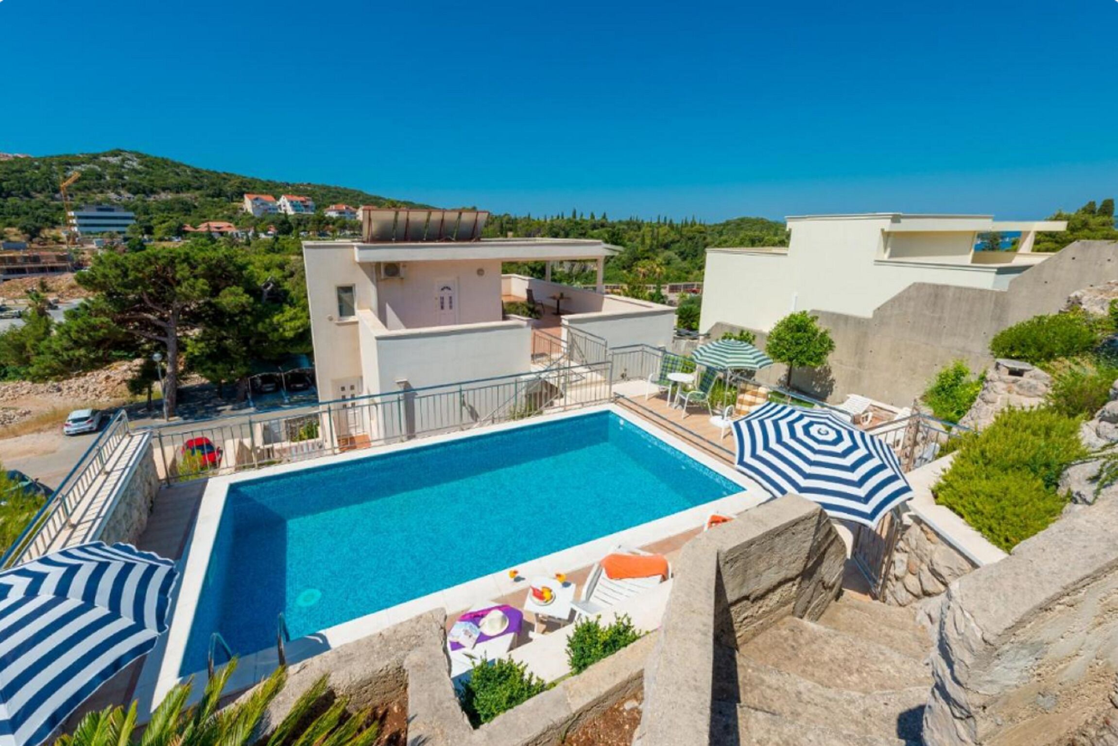 Un espace piscine moderne offrant une vue dégagée sur le paysage environnant, notamment une colline et des bâtiments situés au loin.