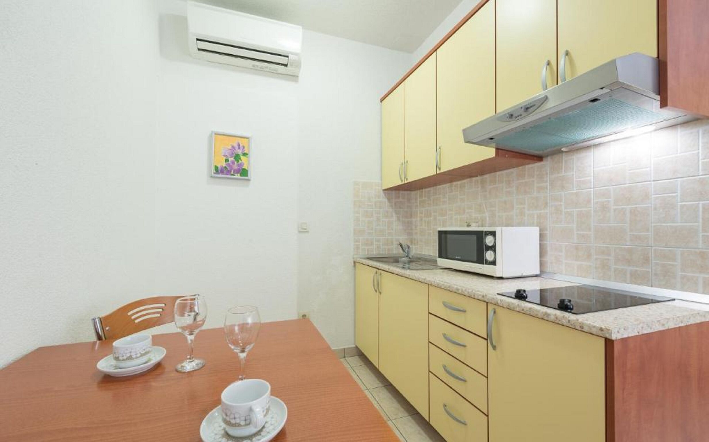 A compact kitchen with yellow cabinets, a microwave, and a small sink.