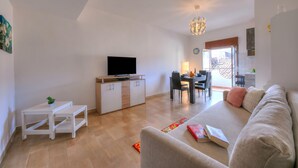 A living room with a sofa, a TV, a dining area, and a kitchen in the background. - Sicilian Charm Close to Taormina (Gaggi)