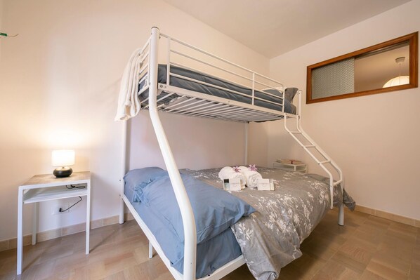 A bunk bed with a desk and a lamp, a mirror, and a small bedside table with a towel and a book. - Sicilian Charm Close to Taormina (Gaggi)