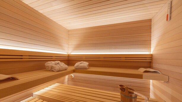 A sauna with wooden benches and benches, a wooden table, and a bucket. - Menina (Livigno)