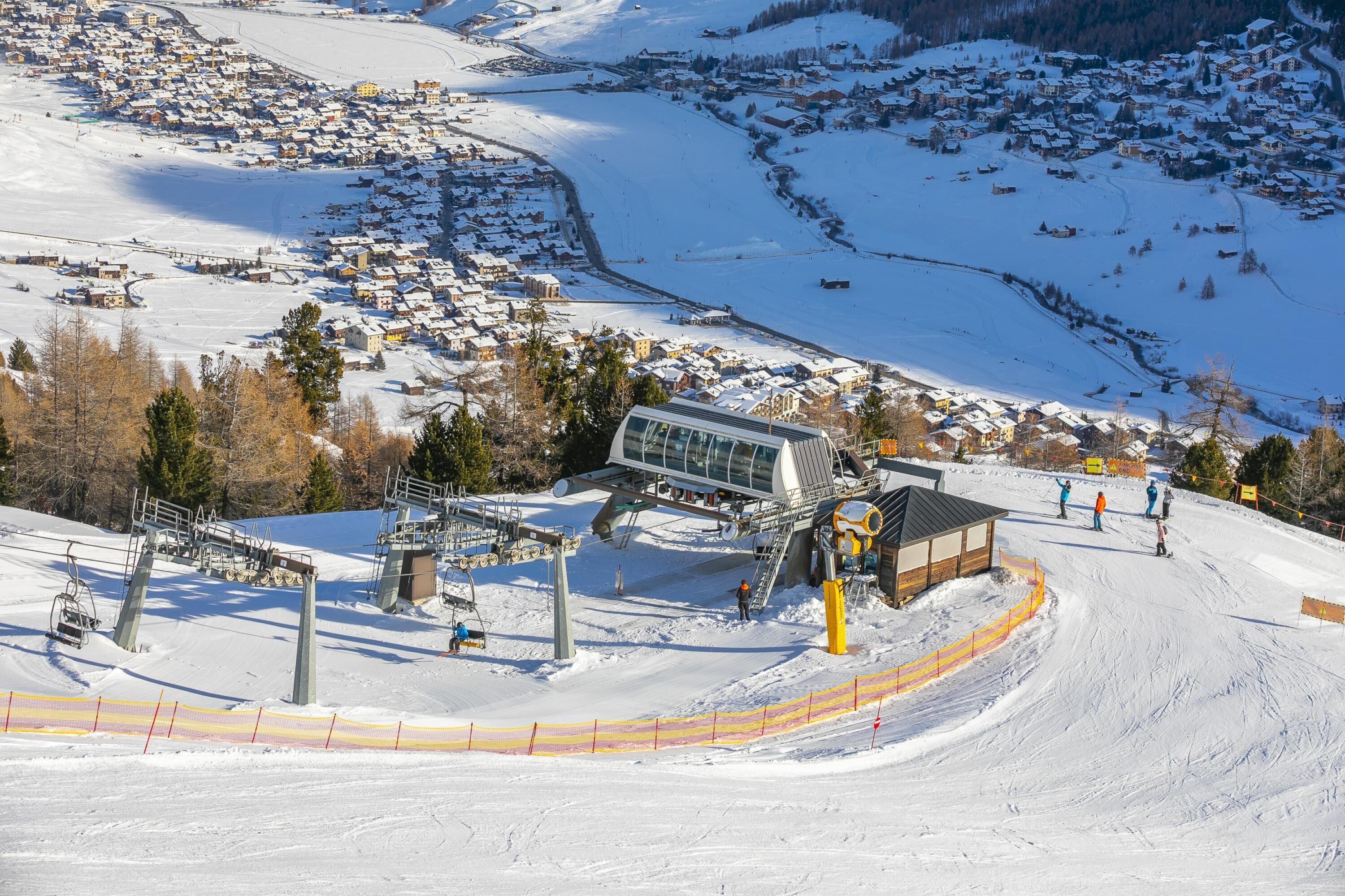 A ski resort with a chairlift, snow-covered slopes, and a town in the background.