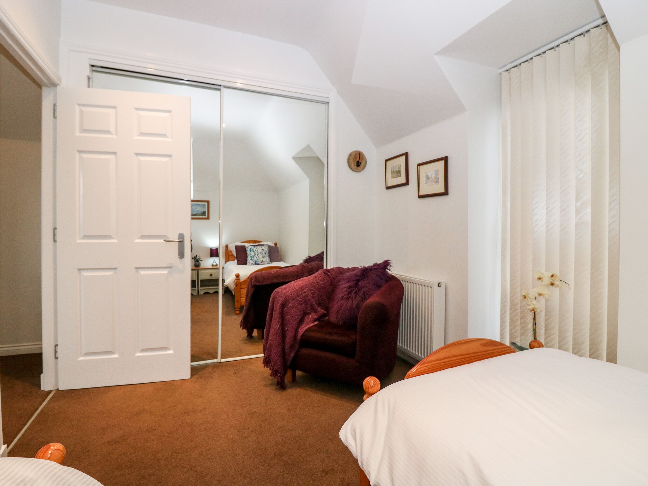 A bedroom with a large mirror, a bed, a chair, and a radiator.