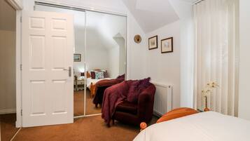 A bedroom with a large mirror, a bed, a chair, and a radiator.