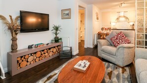 Una sala de estar con televisor, sofá, mesa de centro y chimenea con leña.