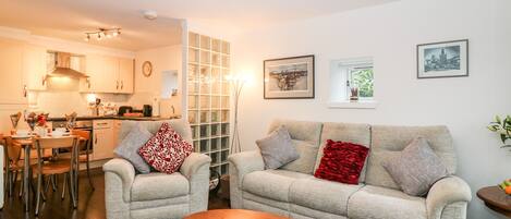 A living room with a sofa, armchairs, a coffee table, and a dining area with chairs and a table.