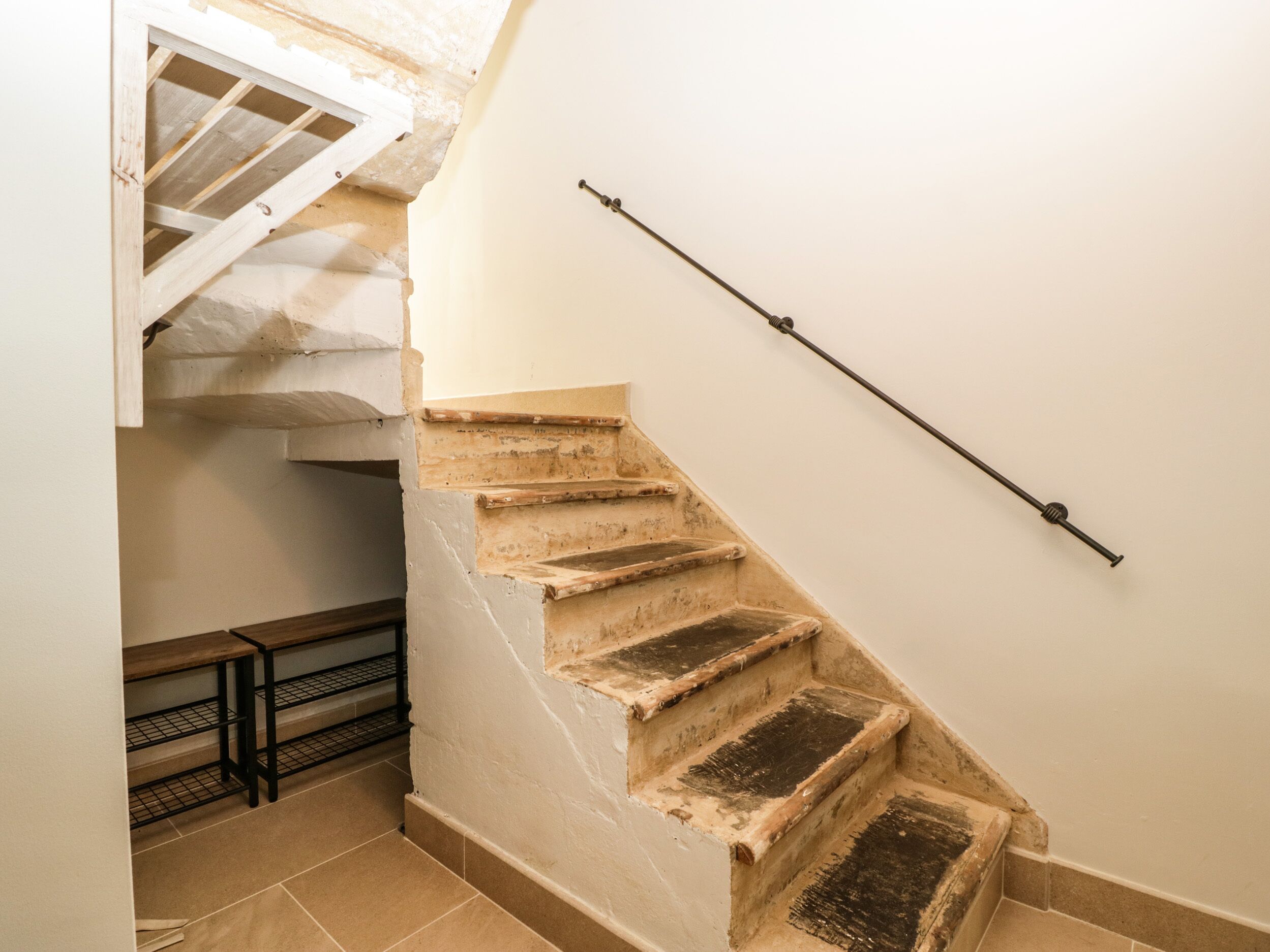 A staircase with a handrail, wooden steps, and a metal banister.