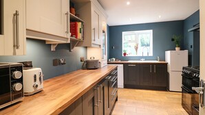 Una cocina moderna con encimeras de madera, electrodomésticos de acero inoxidable y un ventanal que proporciona luz natural.