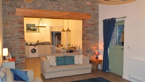 Ein gemütliches Wohnzimmer mit Steinwand, Essbereich und Küche.