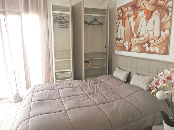 Un dormitorio con cama, armario y un cuadro en la pared.