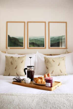 A neatly made bed with a tray of breakfast items including croissants, eggs, and jam, a coffee maker, and a cup of coffee. - Luxury Thatched Country Cottage - Dartmoor, Devon (Exeter)