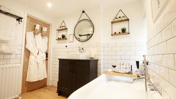 A bathroom with a bathtub, a sink, and a mirror. There are wooden cabinets and shelves with plants.