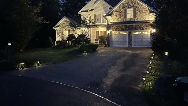 Een tweelaags huis met een gevel van natuursteen, een garage en een verzorgd gazon.