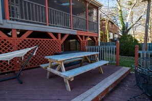 A wooden deck with a picnic table and a hammock.