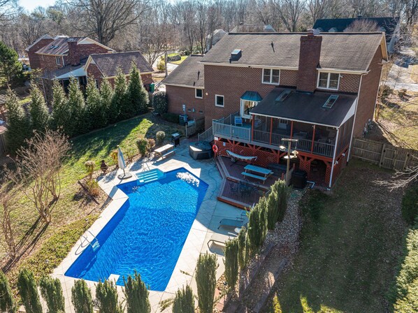 A residential property with a swimming pool, a deck, and a fenced backyard.
