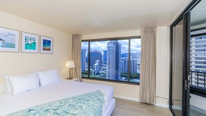 A hotel room with a large bed, a city view, and three framed pictures on the wall. - Discovery Bay, near Ala Moana Shopping Center & the Beach! (Honolulu)