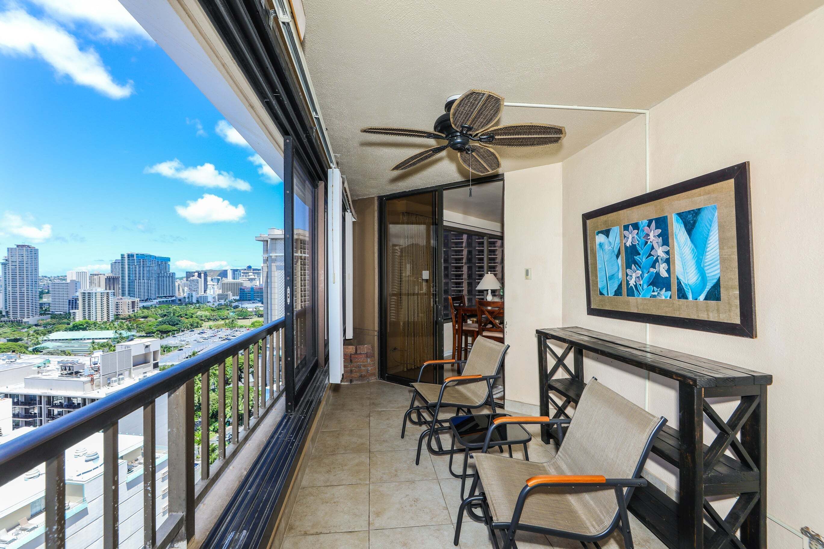 A balcony with a city view, a ceiling fan, and a framed artwork.
