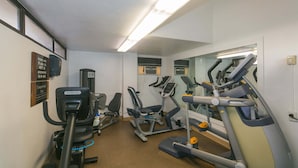 A gym with various exercise machines, a mirror, and a sign on the wall. - Discovery Bay, near Ala Moana Shopping Center & the Beach! (Honolulu)