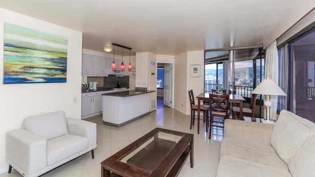 A modern living room with a sofa, a coffee table, and a dining area with chairs and a table. - Discovery Bay, near Ala Moana Shopping Center & the Beach! (Honolulu)
