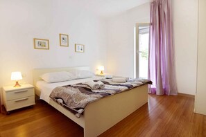 Ein ordentlich bezogenes Bett mit einer gemusterten Decke, zwei Nachttischlampen und einem Nachttisch mit Schubladen.