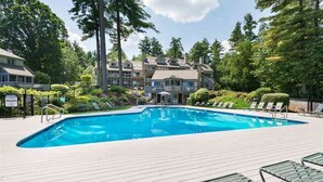 A swimming pool with lounge chairs and a building in the background.