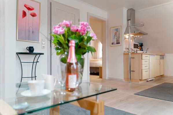 A modern kitchen with a dining area, a vase with flowers, and a painting on the wall.