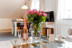 A dining table with a bottle of rosé wine, a vase of pink tulips, and a glass of water.
