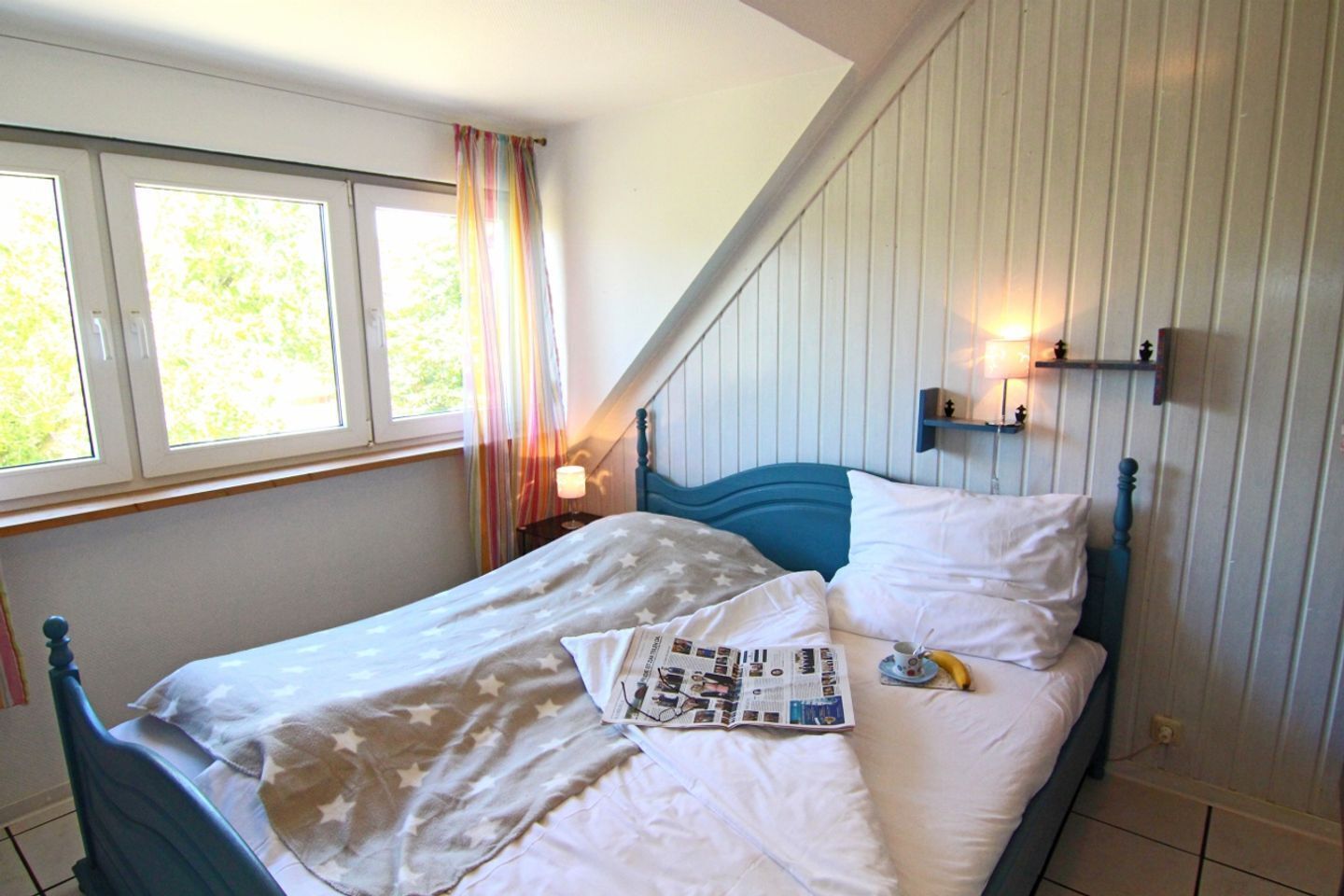 A bedroom with a bed, a window, and a nightstand.
