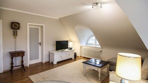A loft-style room with a sloped ceiling, a television, a lamp, and a sofa.