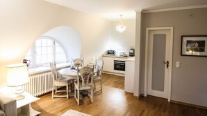 A compact kitchen with a dining area, a radiator, and a chandelier.