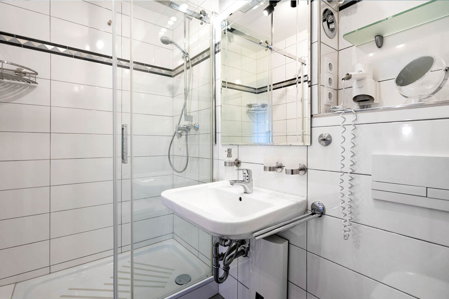 A modern bathroom with a glass shower enclosure, a white sink, and a mirror.